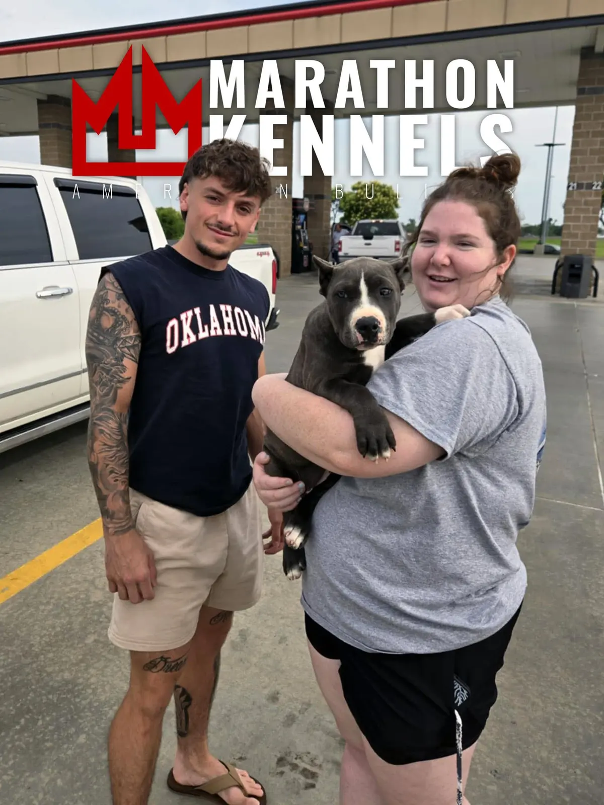 A couple holding their blue and white puppy outside Marathon Kennels
